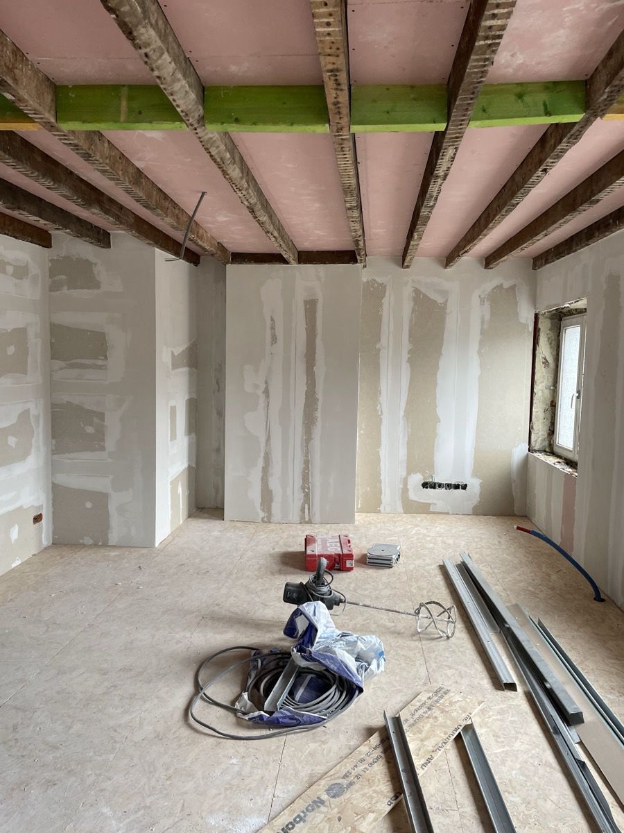 Séjour pendant les travaux : plafonnage, poutres mises à nu, sol OSB